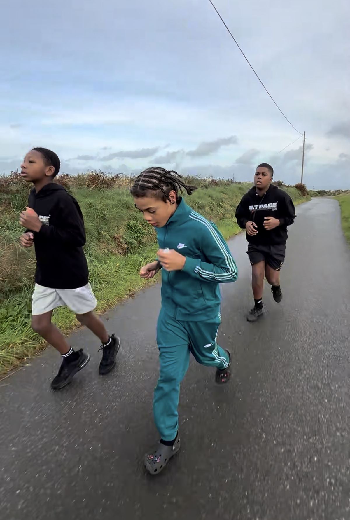 Young people running on a country lane during a residential trip
